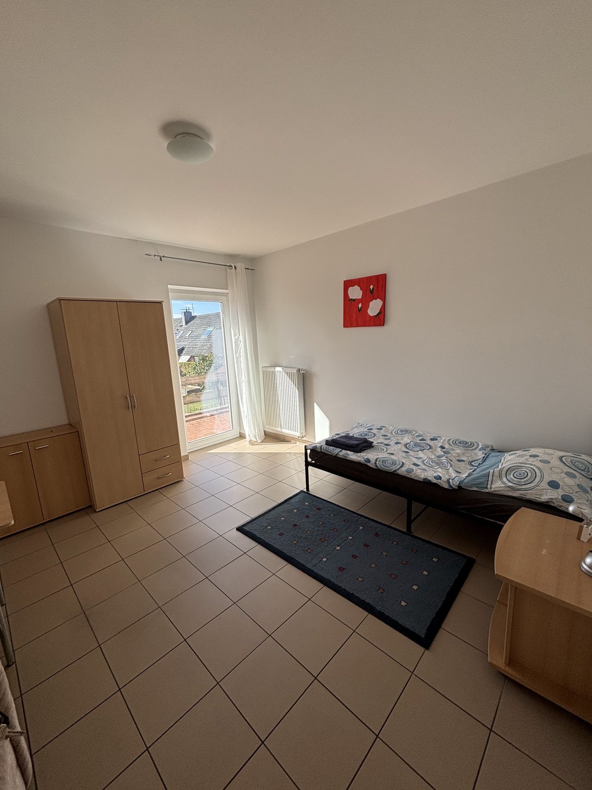 Einzelzimmer mit Kleiderschrank und Bett am Fenster